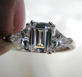 3Ct Emerald Diamond Trilogy Engagement Ring 18K White Gold Over Trillion Accents